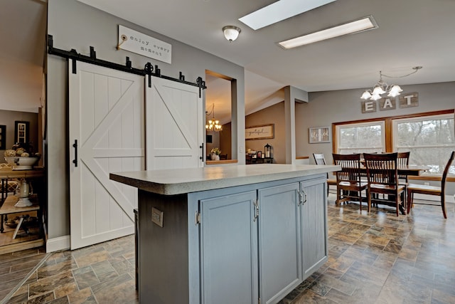 kitchen featuring hanging light fixtures, a barn door, stone finish floor, and an inviting chandelier