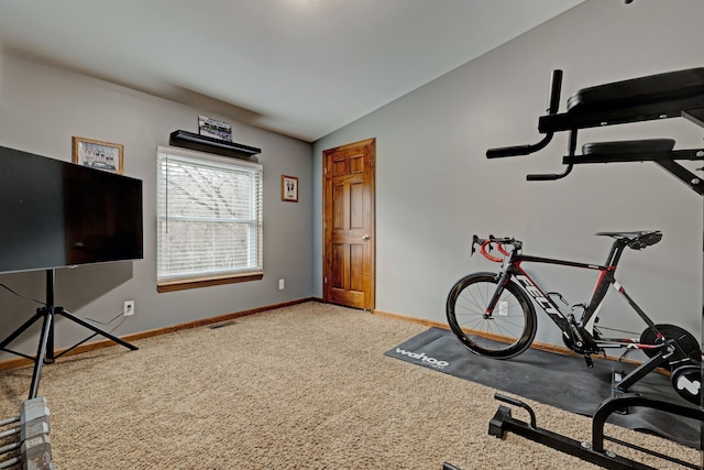 exercise room with lofted ceiling, carpet, and baseboards