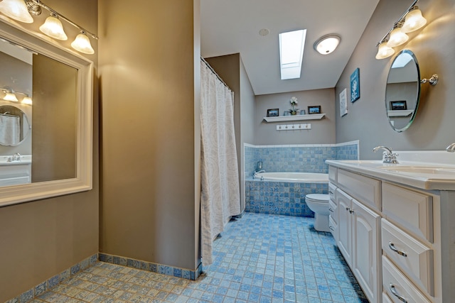 bathroom with a skylight, vanity, toilet, and tiled tub