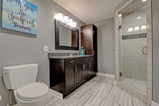 full bath with a stall shower, baseboards, vanity, and toilet