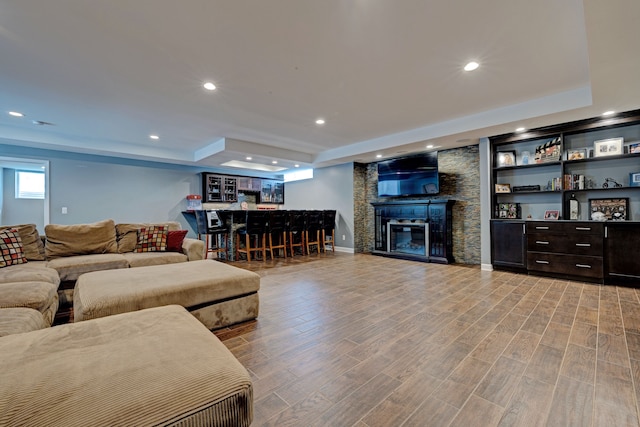 living area featuring a dry bar, a fireplace, wood finished floors, and recessed lighting