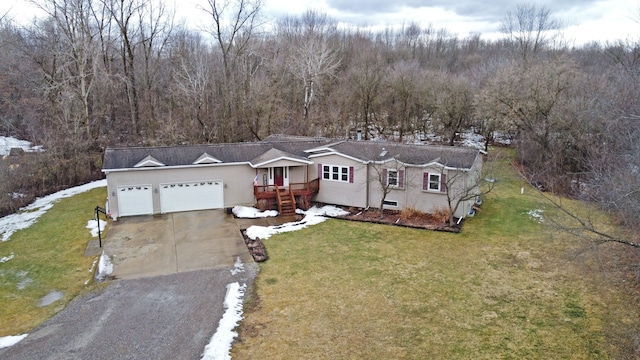 view of front of property with a garage, a front yard, concrete driveway, and a wooded view