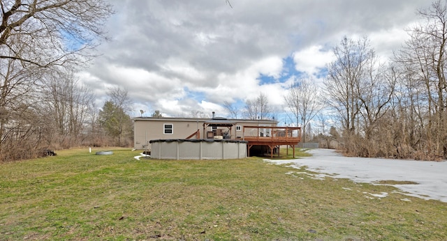 back of property with a covered pool, a lawn, and a wooden deck