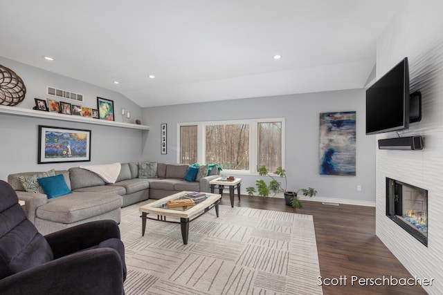 living area with recessed lighting, wood finished floors, visible vents, vaulted ceiling, and a glass covered fireplace