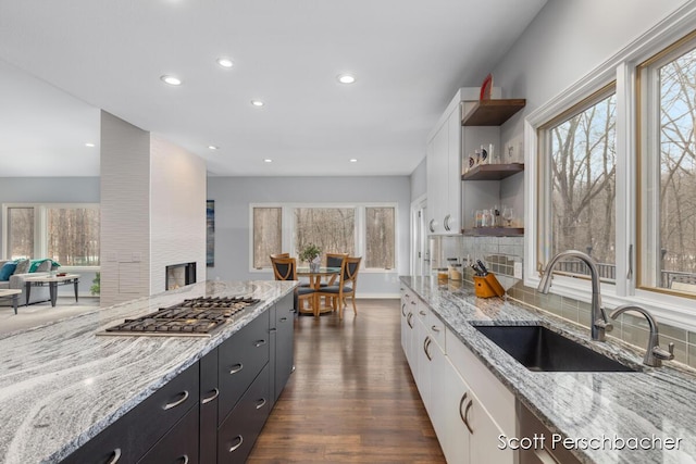 kitchen featuring stainless steel gas cooktop, white cabinets, a sink, and open shelves