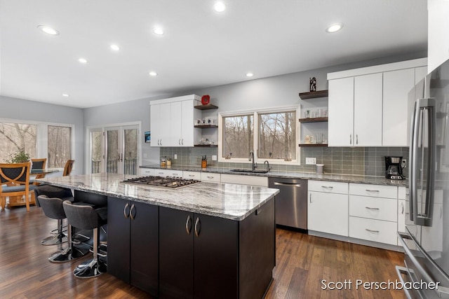 kitchen with open shelves, a sink, a center island, and stainless steel appliances