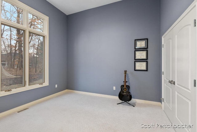 unfurnished room featuring carpet flooring, visible vents, and baseboards