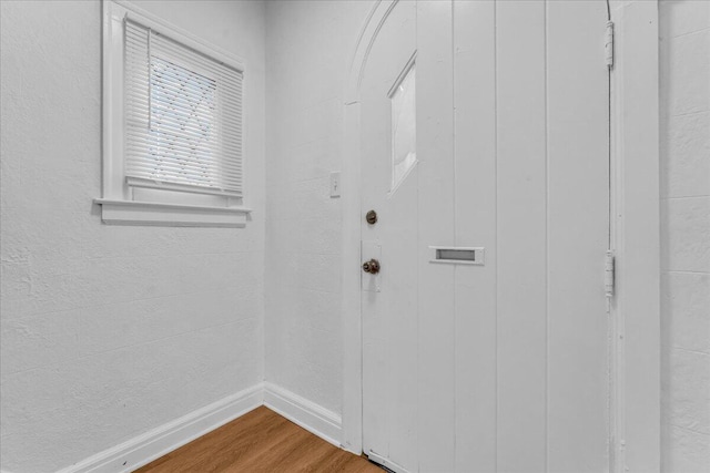 doorway featuring baseboards and wood finished floors