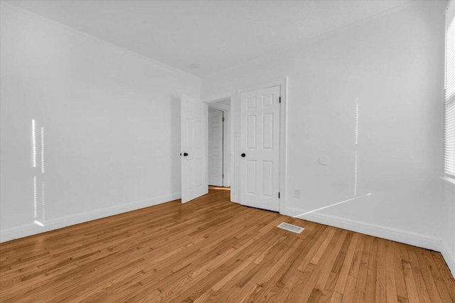 unfurnished room featuring light wood-style floors, visible vents, and baseboards