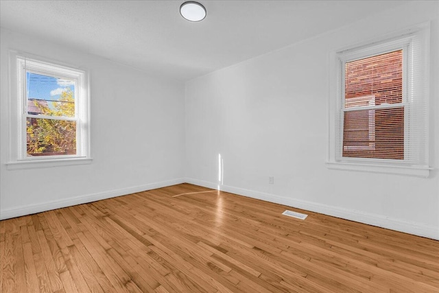 spare room with light wood-type flooring, baseboards, and visible vents