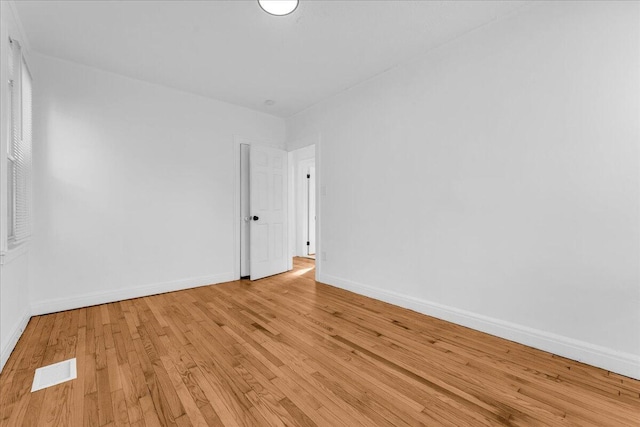 unfurnished room featuring light wood-style flooring, visible vents, and baseboards