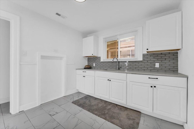 kitchen with marble finish floor, visible vents, a sink, and white cabinetry