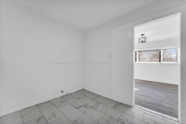 empty room featuring marble finish floor and baseboards