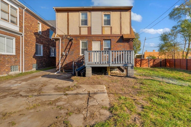 rear view of property featuring a yard, fence, a deck, and brick siding