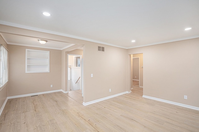 spare room with light wood-type flooring, built in features, visible vents, and baseboards