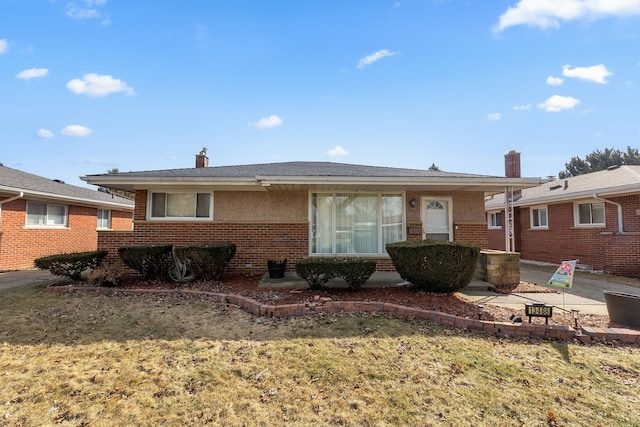 view of front of home featuring brick siding, a chimney, and a patio area