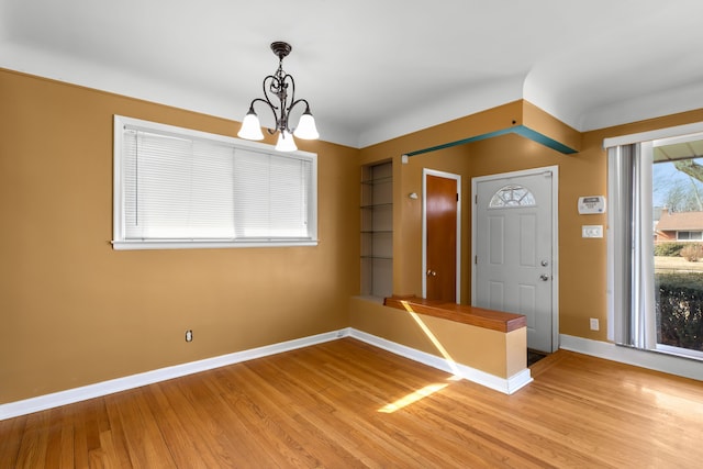 entrance foyer with a chandelier, light wood-style flooring, and baseboards