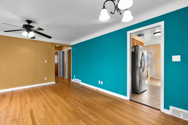 spare room featuring light wood-style flooring, visible vents, and ceiling fan