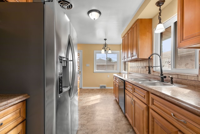 kitchen featuring stainless steel appliances, a sink, visible vents, and brown cabinets