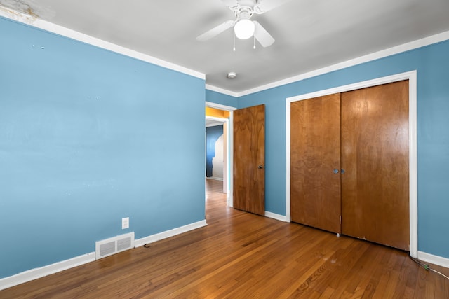 unfurnished bedroom featuring a ceiling fan, visible vents, baseboards, and wood finished floors