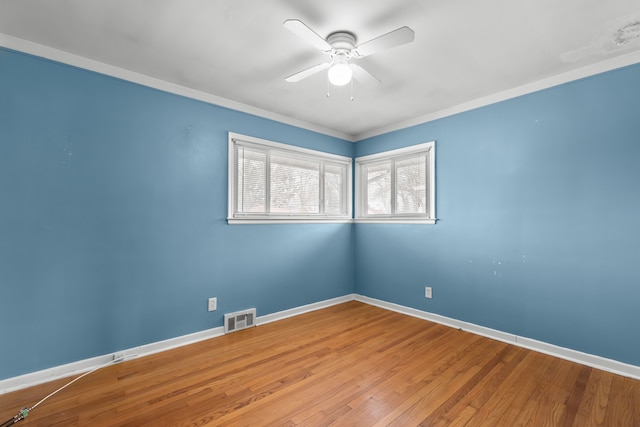 empty room with a ceiling fan, visible vents, baseboards, and wood finished floors