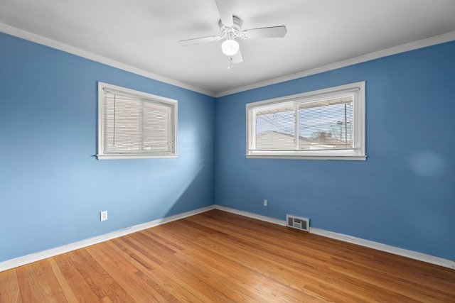 unfurnished room featuring a ceiling fan, baseboards, visible vents, light wood-style floors, and ornamental molding