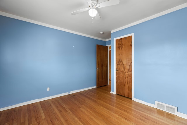 unfurnished room with baseboards, wood finished floors, visible vents, and a ceiling fan