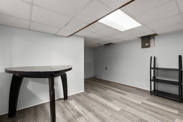 finished below grade area with wood finished floors, a paneled ceiling, and baseboards