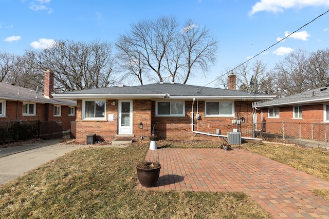 view of front of property with brick siding, a chimney, a front yard, and fence