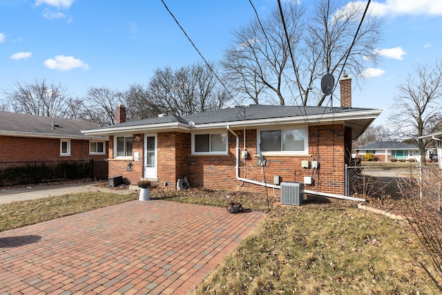 single story home with a chimney, fence, and brick siding