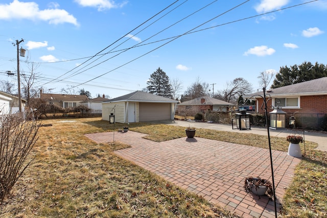 view of yard featuring a patio area, fence, a detached garage, and an outdoor structure