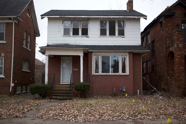 view of front of home featuring a shingled roof, a chimney, and brick siding