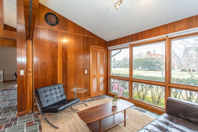 living room featuring lofted ceiling, wooden walls, and visible vents