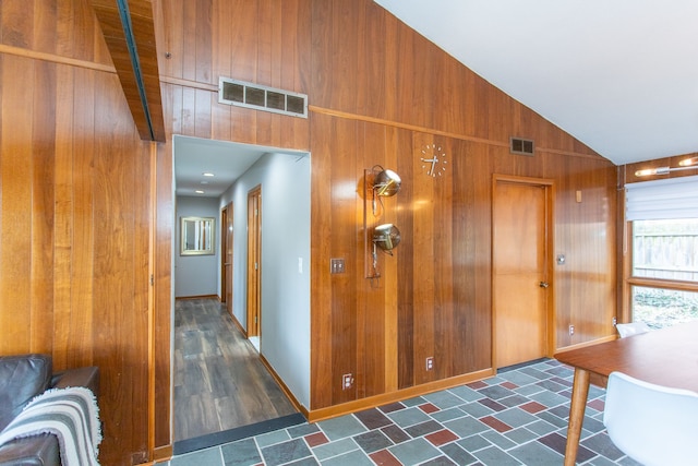 corridor featuring wooden walls, visible vents, and vaulted ceiling