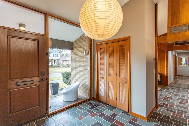 foyer featuring lofted ceiling, visible vents, plenty of natural light, and baseboards