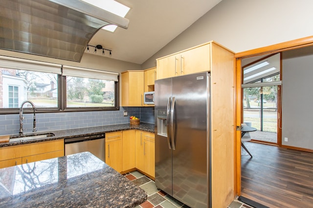 kitchen with lofted ceiling, decorative backsplash, appliances with stainless steel finishes, light brown cabinets, and a sink