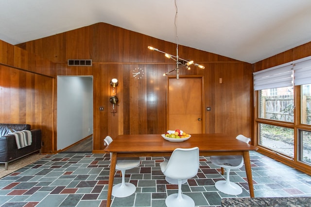 dining area featuring lofted ceiling, wood walls, and visible vents