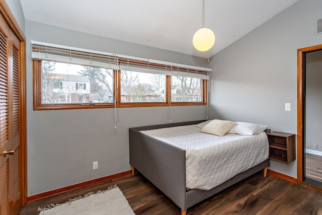 bedroom with a closet, visible vents, vaulted ceiling, wood finished floors, and baseboards