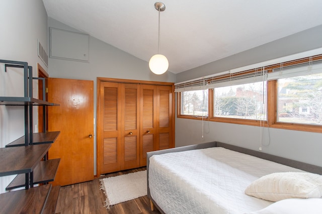 bedroom with a closet, visible vents, vaulted ceiling, and wood finished floors