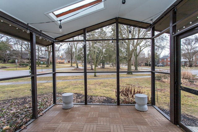 unfurnished sunroom with vaulted ceiling with skylight and rail lighting