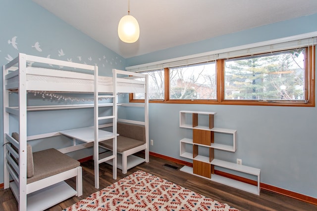 bedroom featuring lofted ceiling, visible vents, baseboards, and wood finished floors