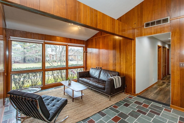 living area featuring high vaulted ceiling, wood walls, visible vents, and baseboards