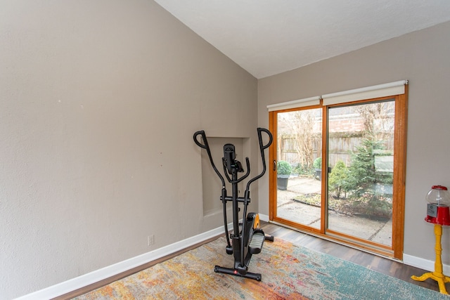 workout room featuring lofted ceiling, wood finished floors, and baseboards