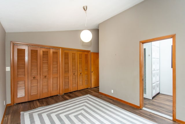 unfurnished bedroom featuring baseboards, vaulted ceiling, and wood finished floors