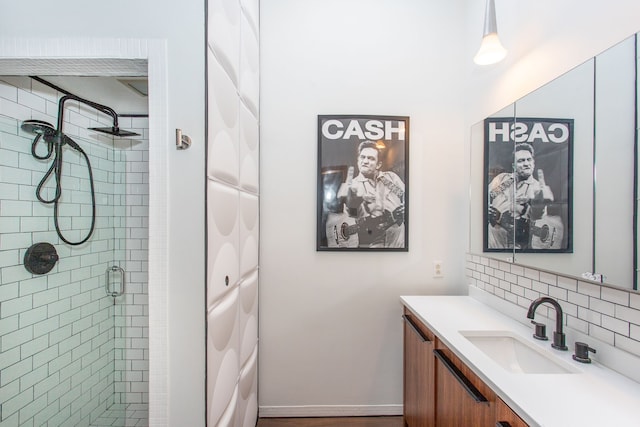 bathroom featuring a stall shower, backsplash, vanity, and baseboards