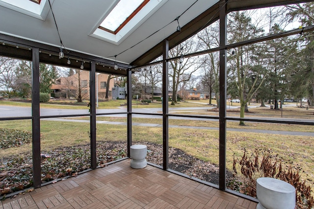 unfurnished sunroom with a healthy amount of sunlight and vaulted ceiling with skylight