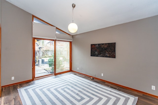 spare room featuring vaulted ceiling, wood finished floors, visible vents, and baseboards