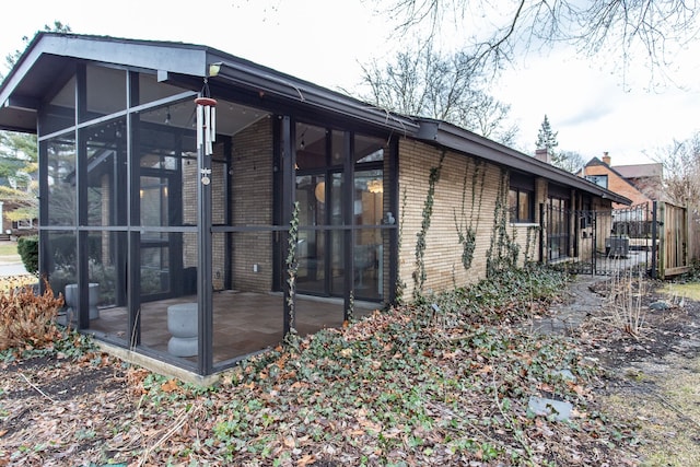 view of home's exterior with brick siding and a sunroom