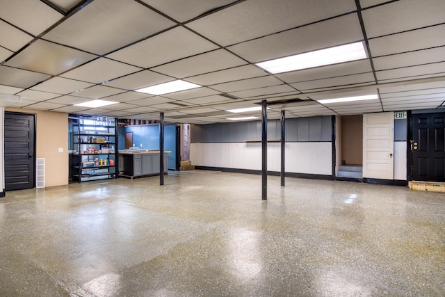 finished below grade area featuring a paneled ceiling, visible vents, and baseboards