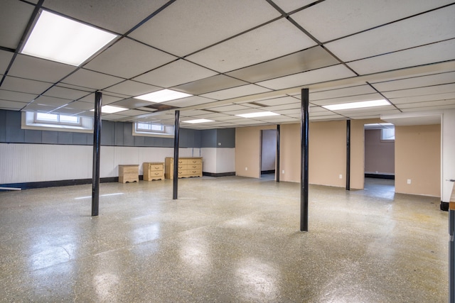 basement with a drop ceiling and baseboards